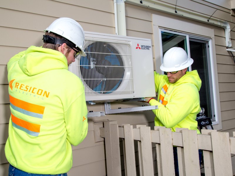 Construction workers help install a heat pump.