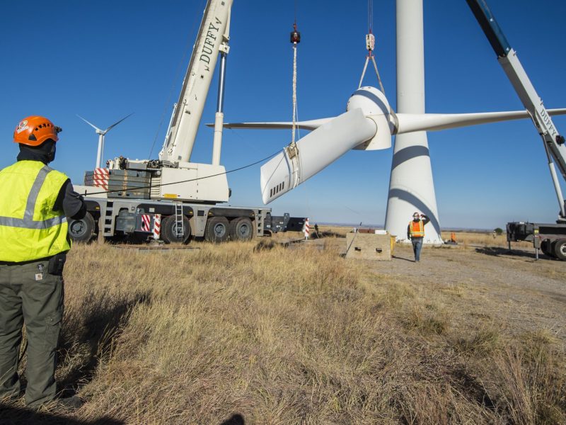 Engineers and technicians lower the rotor and blades off of a wind turbine.