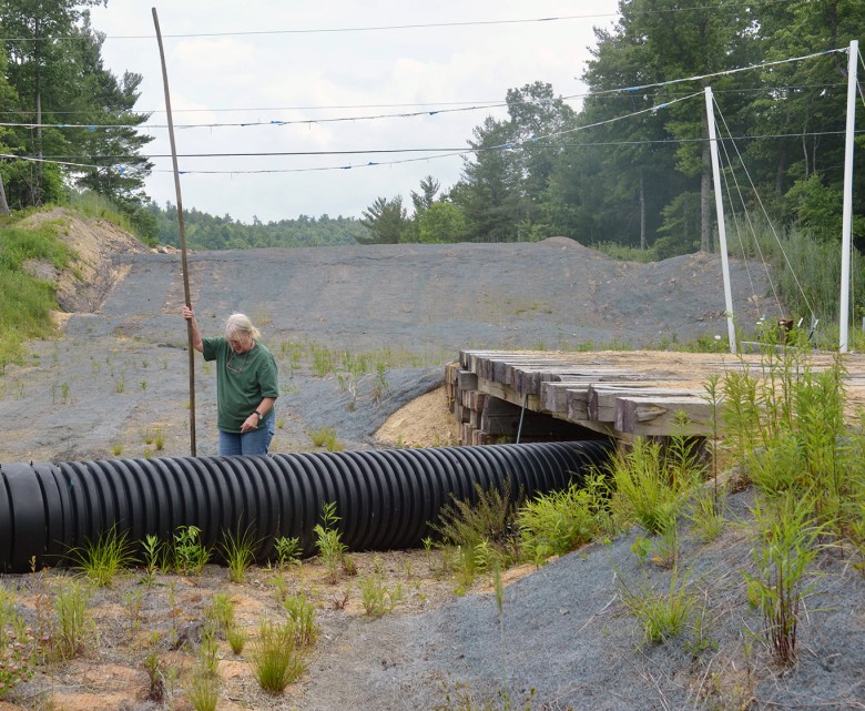 Red Terry measures the water that has seeped into holes bored on the MVP path on family property near her house. 