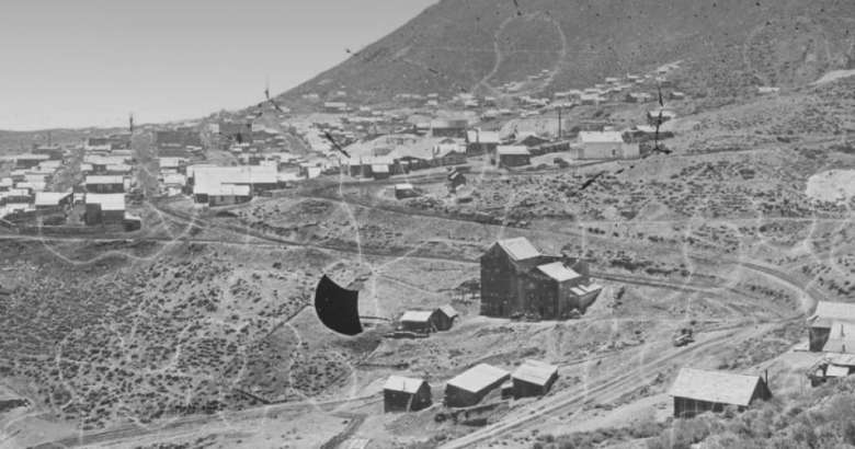 A black and white photograph with dozens of wooden home structures along a mountainside.