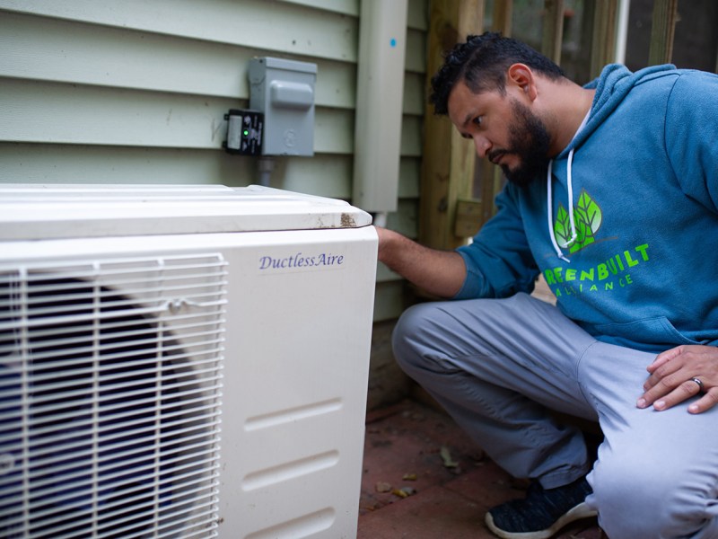 Kelvin Bonilla, a staff member at Energy Savers Network, inspects an heat pump.