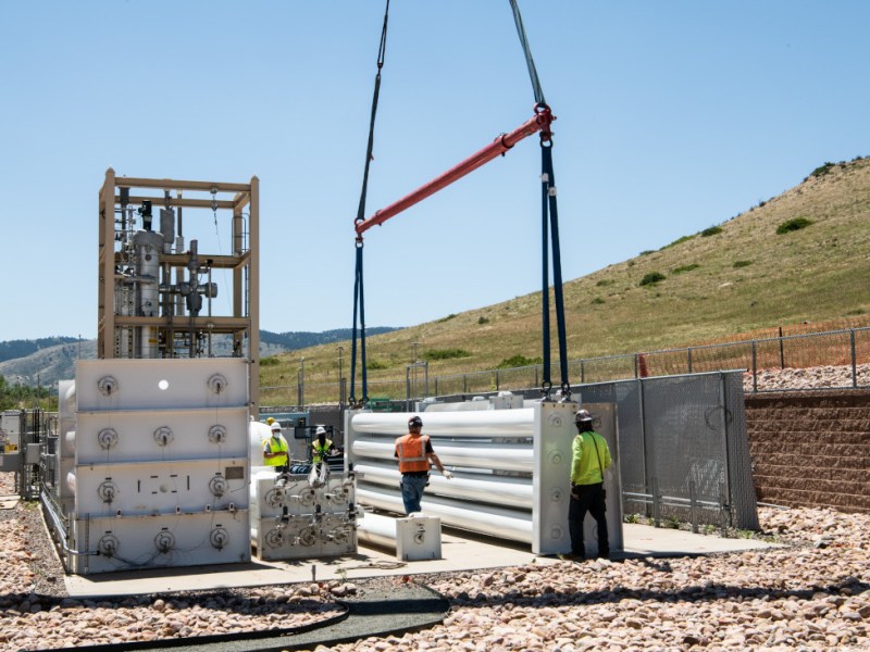 A crane lifts a hydrogen storage tank into place at an outdoor federal research facility in Colorado