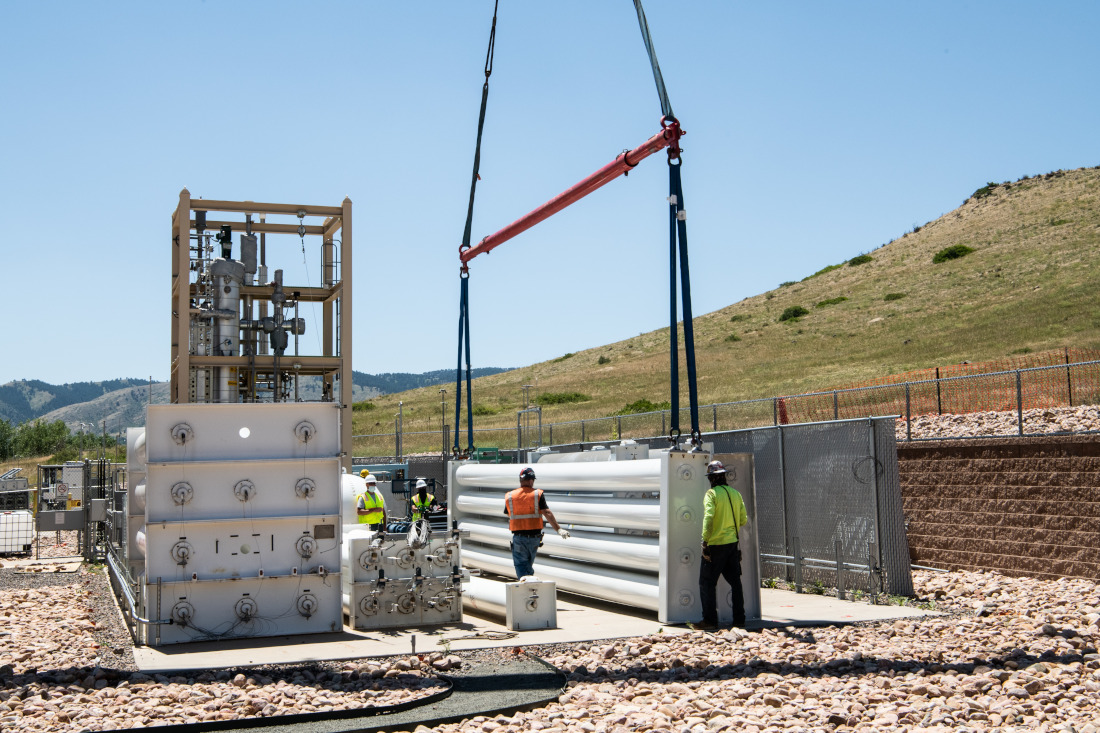 A crane lifts a hydrogen storage tank into place at an outdoor federal research facility in Colorado
