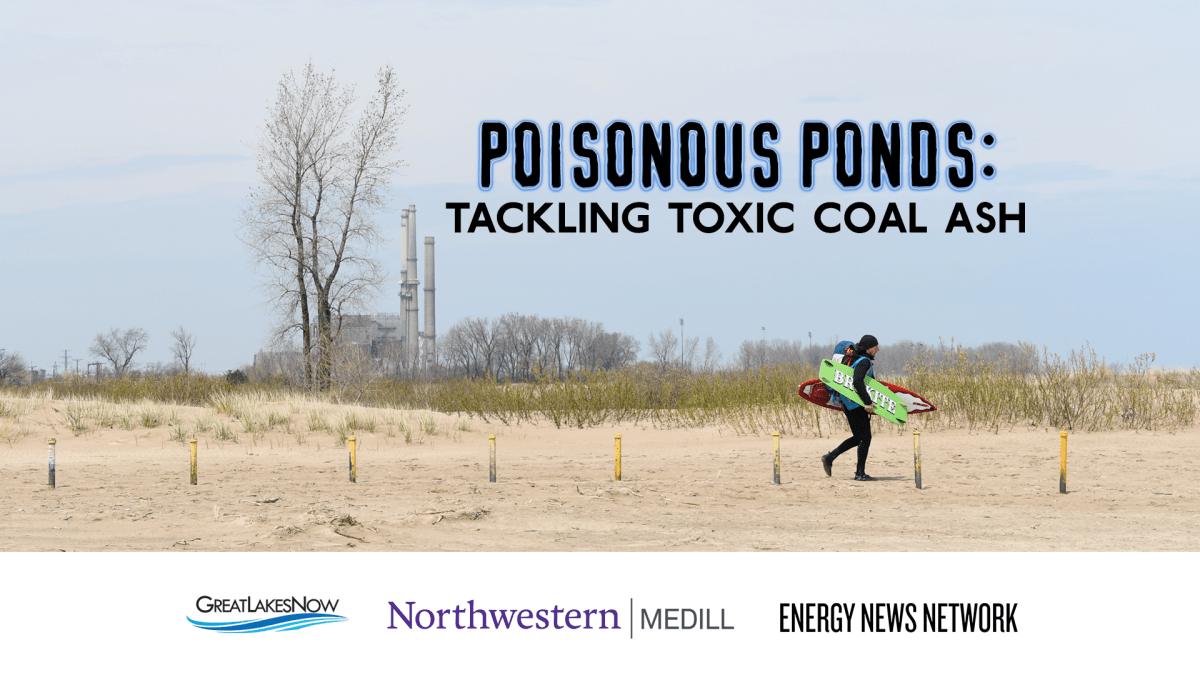 The three smokestacks of Waukegan Generating Station are visible from a nearby beach, where a passerby prepares to surf in Lake Michigan.